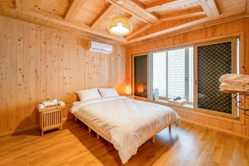1 dormitorio con 1 cama grande en una habitación con paredes de madera en Elon Hanok Pension, en Yeosu