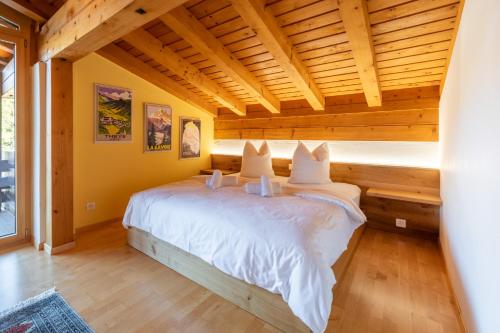 - une chambre avec un lit blanc dans une pièce dotée de plafonds en bois dans l'établissement LAAX Homes - Casa la Streia, à Laax