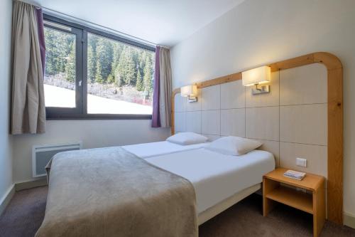 ein Hotelzimmer mit einem Bett und einem Fenster in der Unterkunft Résidence Pierre & Vacances La Forêt in Flaine