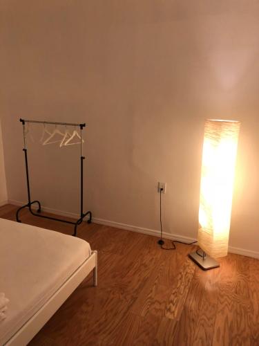布魯克林的住宿－Beachside Brooklyn，一间卧室配有一张床和一盏灯,铺有木地板