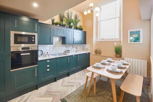 una cocina con armarios verdes y una mesa con platos. en Host & Stay - No.33, en Tynemouth