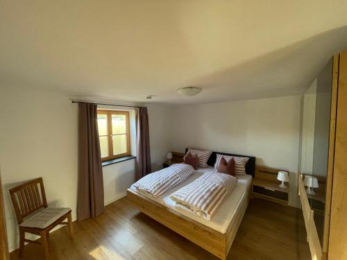 1 dormitorio con 1 cama, 1 silla y 1 ventana en Ferienwohnung Obstgarten, en Irschenberg