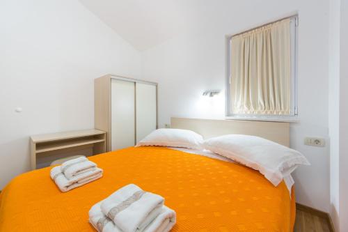ein Schlafzimmer mit einem orangenen Bett mit Handtüchern darauf in der Unterkunft Apartments Sunrise in Brist