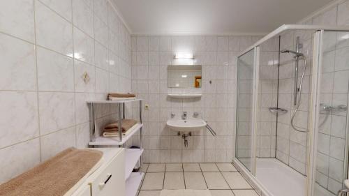 a white bathroom with a shower and a sink at Appartements KALSWIRT in Kirchberg in Tirol