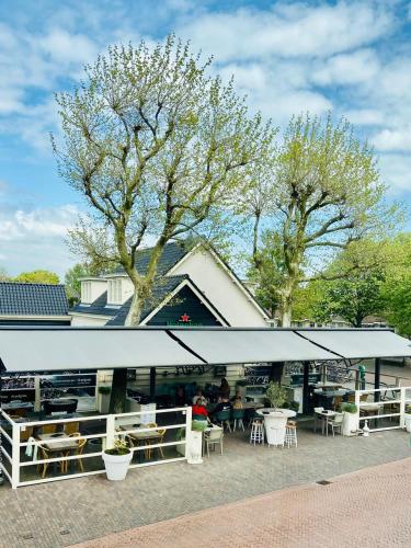 a building with tables and chairs and trees at Studio de Pelgrim in Vrouwenpolder