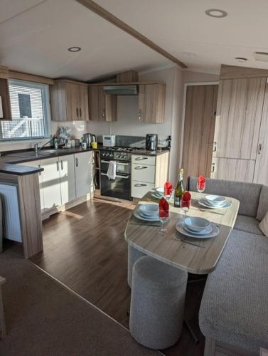 a kitchen with a wooden table and a kitchen with a table and chairs at Sleeps 6 Modern and bright Caravan Littlesea Haven Weymouth in Weymouth