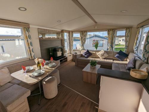 ein Wohnzimmer mit Sofas und Tischen in einem Wohnwagen in der Unterkunft Sleeps 6 Modern and bright Caravan Littlesea Haven Weymouth in Weymouth