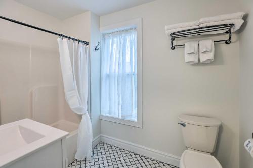 a white bathroom with a toilet and a window at Walkable Sodus Point Retreat Less Than 1 Mi to Lake in Sodus