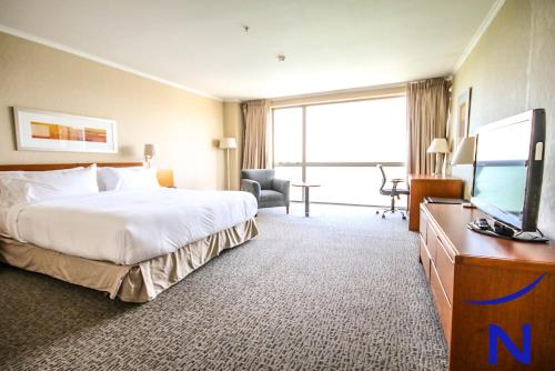 um quarto de hotel com uma cama e uma televisão de ecrã plano em Novotel Puerto Montt em Puerto Montt