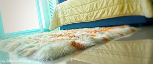 a comforter laying on a bed with a pillow at My Dallyne's Homestay at Mutiara Ville Cyberjaya in Cyberjaya