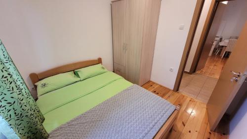 Dormitorio pequeño con cama con sábanas verdes en Zlatibor Apartmani DM Tornik en Zlatibor