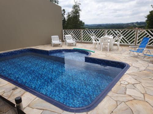 a swimming pool with chairs and a table and chairs at Casa ChaCha - Paz e Bem in Águas de São Pedro