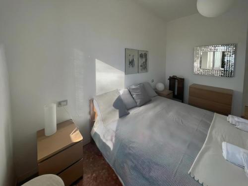 a white bedroom with a bed and a night stand at Casa Vacanze Le Violette in Brunate