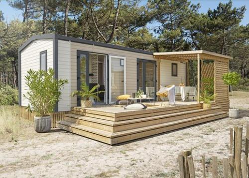a tiny house with a deck in the sand at Camping Du Paquier Fané in Chagny