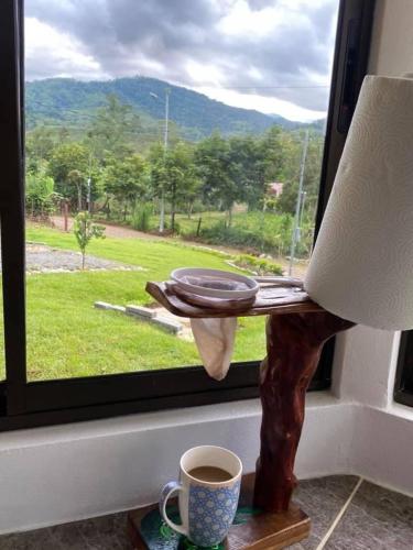 eine Tasse Kaffee und ein Teller auf einem Tisch neben einem Fenster in der Unterkunft Casa anwara in San Isidro