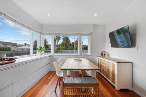 a dining room with a table and a tv at Amazing Home By Beach - Fully Aircon-ed - Wifi in Auckland