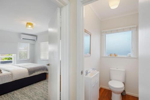 uma casa de banho branca com uma cama e um WC em Amazing Home By Beach - Fully Aircon-ed - Wifi em Auckland