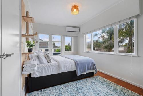 a white bedroom with a bed and a window at Amazing Home By Beach - Fully Aircon-ed - Wifi in Auckland