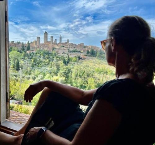 una mujer sentada en una ventana mirando a una ciudad en B&B Il Fienile San Gimignano en San Gimignano