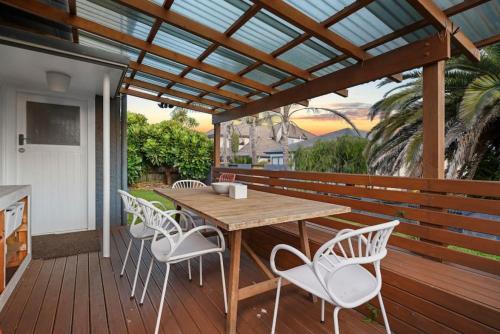 a wooden deck with a wooden table and chairs at Amazing Home By Beach - Fully Aircon-ed - Wifi in Auckland