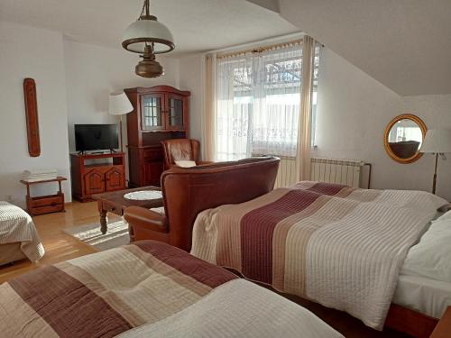 a bedroom with two beds and a chair and a television at Willa Rosa in Kajetany