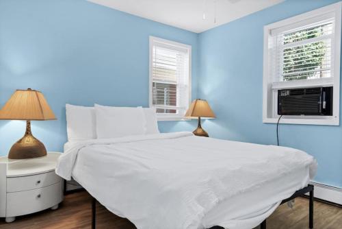 a blue bedroom with a white bed and two lamps at Gammys Beach Getaway Sleeps 20 2 blocks to Beach in Ventnor City