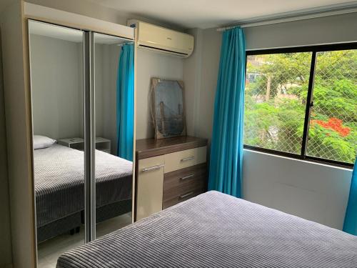 um quarto com 2 camas e uma janela com cortinas azuis em Lindo apto reformado no coração de BC no Balneário Camboriú