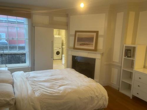 een slaapkamer met een wit bed en een open haard bij Spacious 2 Bedroom Apartment in the heart of Soho. in Londen