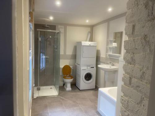 een badkamer met een douche, een toilet en een wasmachine bij Spacious 2 Bedroom Apartment in the heart of Soho. in Londen