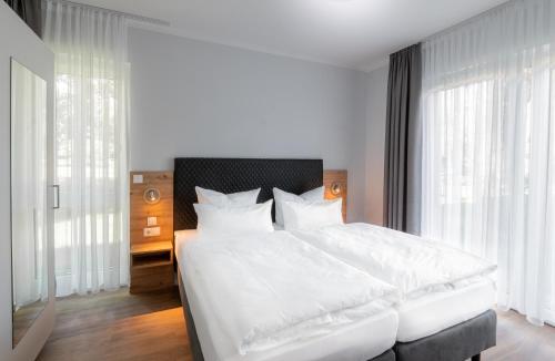 1 dormitorio con 1 cama blanca grande con almohadas blancas en Sporthotel Neuruppin - Apartmenthaus mit Ferienwohnungen, en Neuruppin