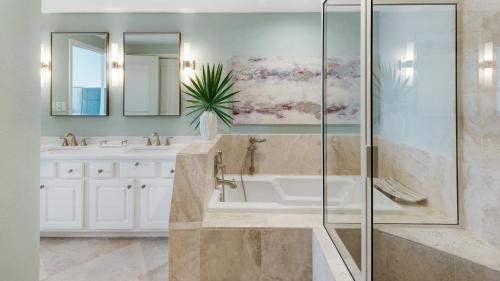 a bathroom with a tub and a glass shower at Tranquillity 340 in Panama City Beach