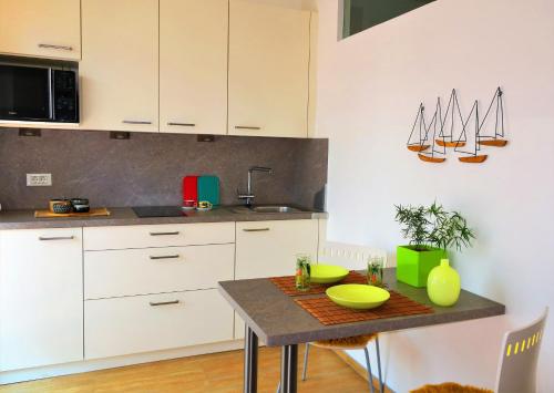 a kitchen with white cabinets and a table with yellow dishes on it at Appartement Piave, Meran Zentrum, mit Garage in Merano