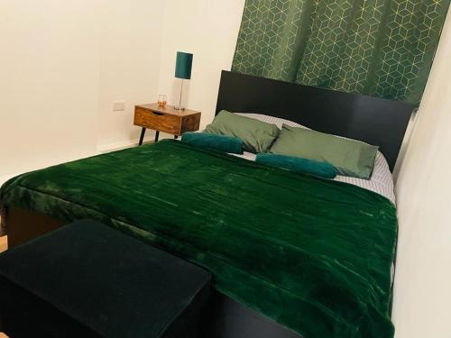 a bedroom with a green bed with a side table at London Luxury Apartment with Private Jacuzzi Hot tub & Sauna in London