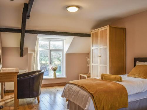 a bedroom with a bed and a desk and a window at Woodland Cottage in Pont Yates