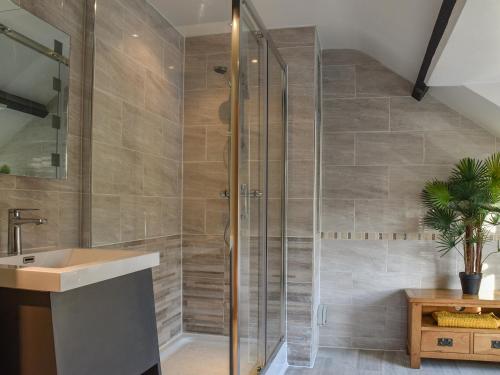 a bathroom with a glass shower and a sink at Woodland Cottage in Pont Yates