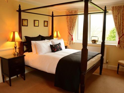 sypialnia z łóżkiem z baldachimem i oknem w obiekcie Dunkery Beacon Country House w mieście Wootton Courtenay