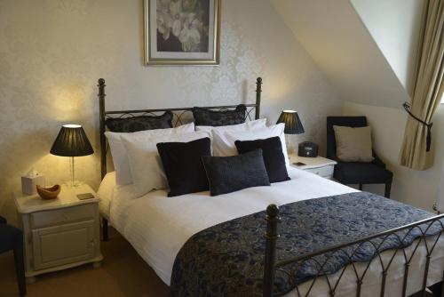 ein Schlafzimmer mit einem großen Bett mit schwarzen und weißen Kissen in der Unterkunft Dunkery Beacon Country House in Wootton Courtenay