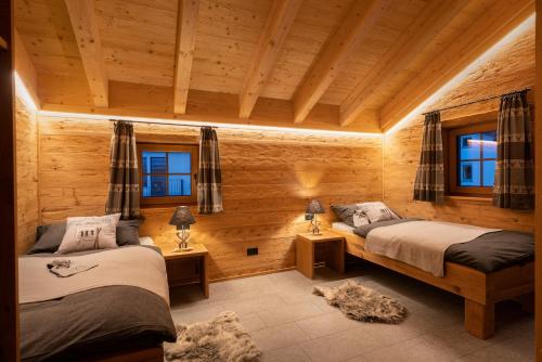 two beds in a room with wooden walls and windows at Engadin Chalet - Private Spa Retreat & Appart -St Moritz - Val Bever in Bever