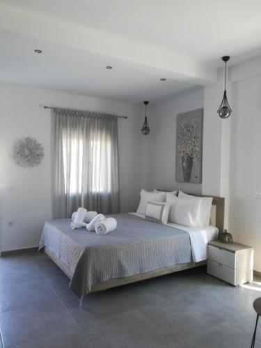a white bedroom with a large bed with white pillows at Aiolos Blu Luxury Apartments in Nea Roda