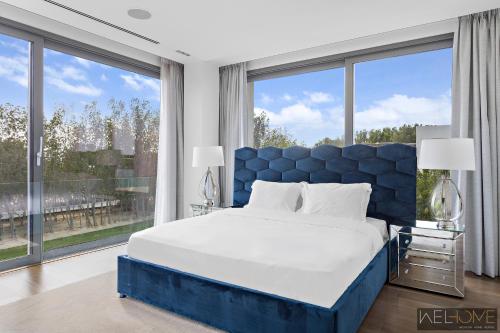 a bedroom with a blue bed and large windows at WelHome - Extraordinary Giant Water Villa on Nurai Island in Abu Dhabi