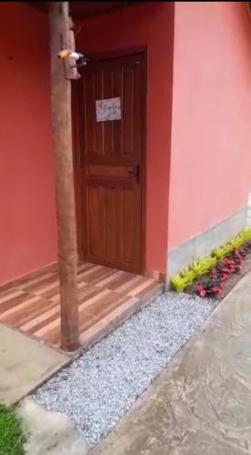 a house with a wooden door and some flowers at Chalés Mimar Lumiar Suítes individuais in Lumiar