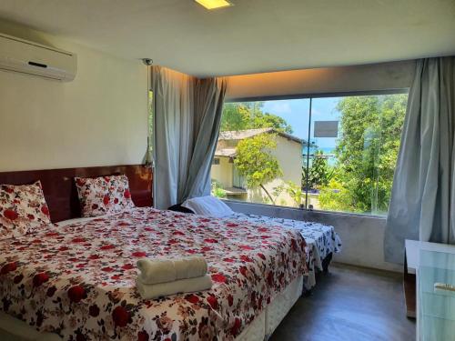 a bedroom with a bed and a large window at Villas do Pratagy resort Maceió próximo praia in Maceió