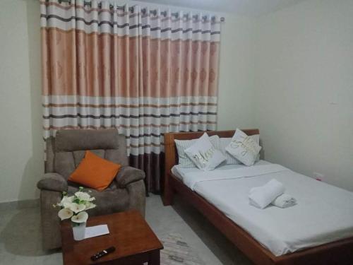 a room with a bed and a chair and a table at Eden's Studio apartment in Syokimau