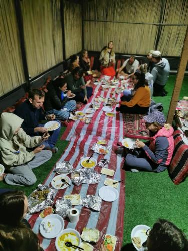 a group of people sitting around a long table of food at Panorama Camp Bidiya in Al Wāşil