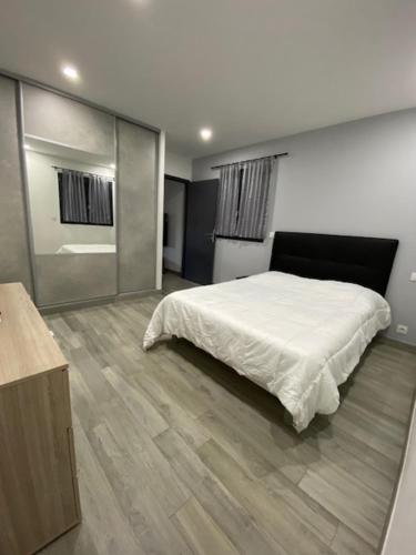 een slaapkamer met een wit bed en een houten vloer bij Maison récente de 50 m2 pour 4 personnes in Porto-Vecchio