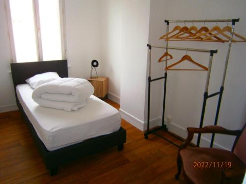 une chambre avec un lit avec des draps blancs et des serviettes dans l'établissement Maison proche de la plage, à Fécamp