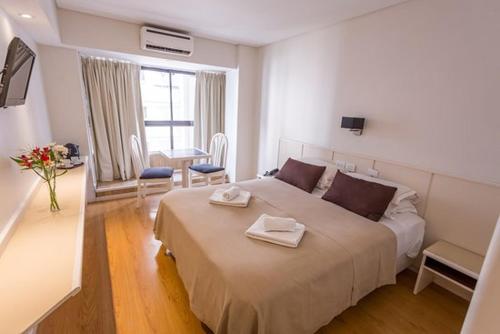 1 dormitorio con 1 cama grande y 2 toallas. en Hotel Dion en Mar del Plata