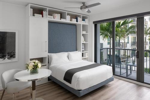 a bedroom with a bed and a table and a balcony at AKA West Palm in West Palm Beach