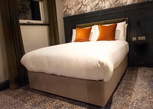 a bedroom with a large bed with orange pillows at The Coachman Hotel in Kilsyth