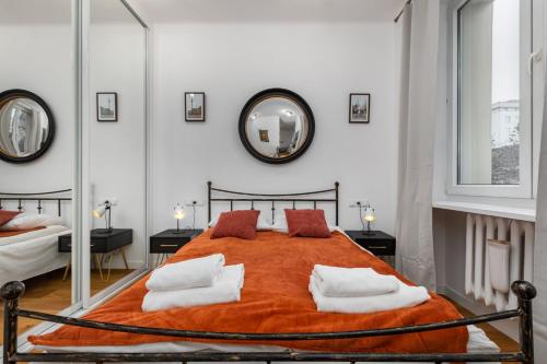 ein Schlafzimmer mit einem großen orangenen Bett mit Spiegeln in der Unterkunft Nowy Świat 47a by Homeprime in Warschau